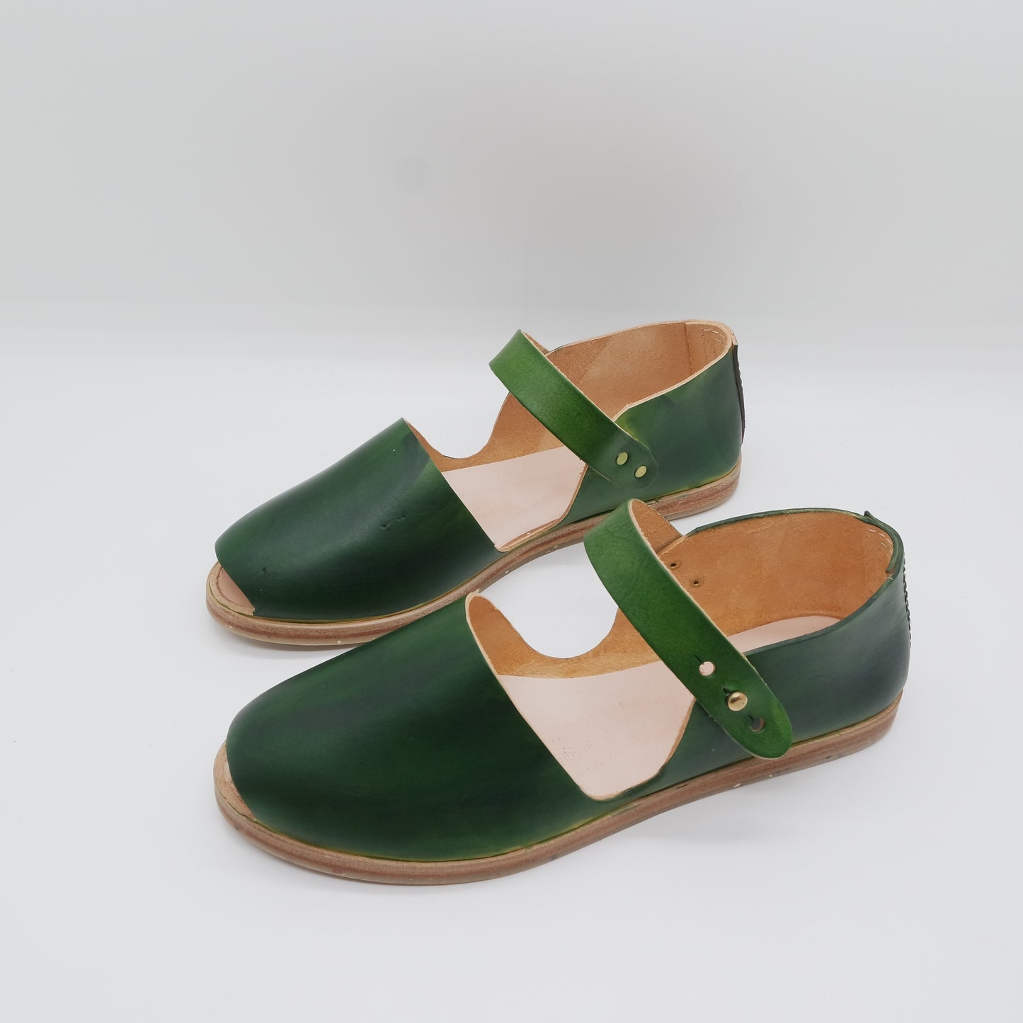 a pair of  handmade green shoes on a white surface