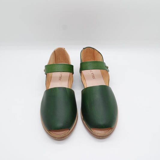 a pair of handmade green shoes sitting on top of a white surface
