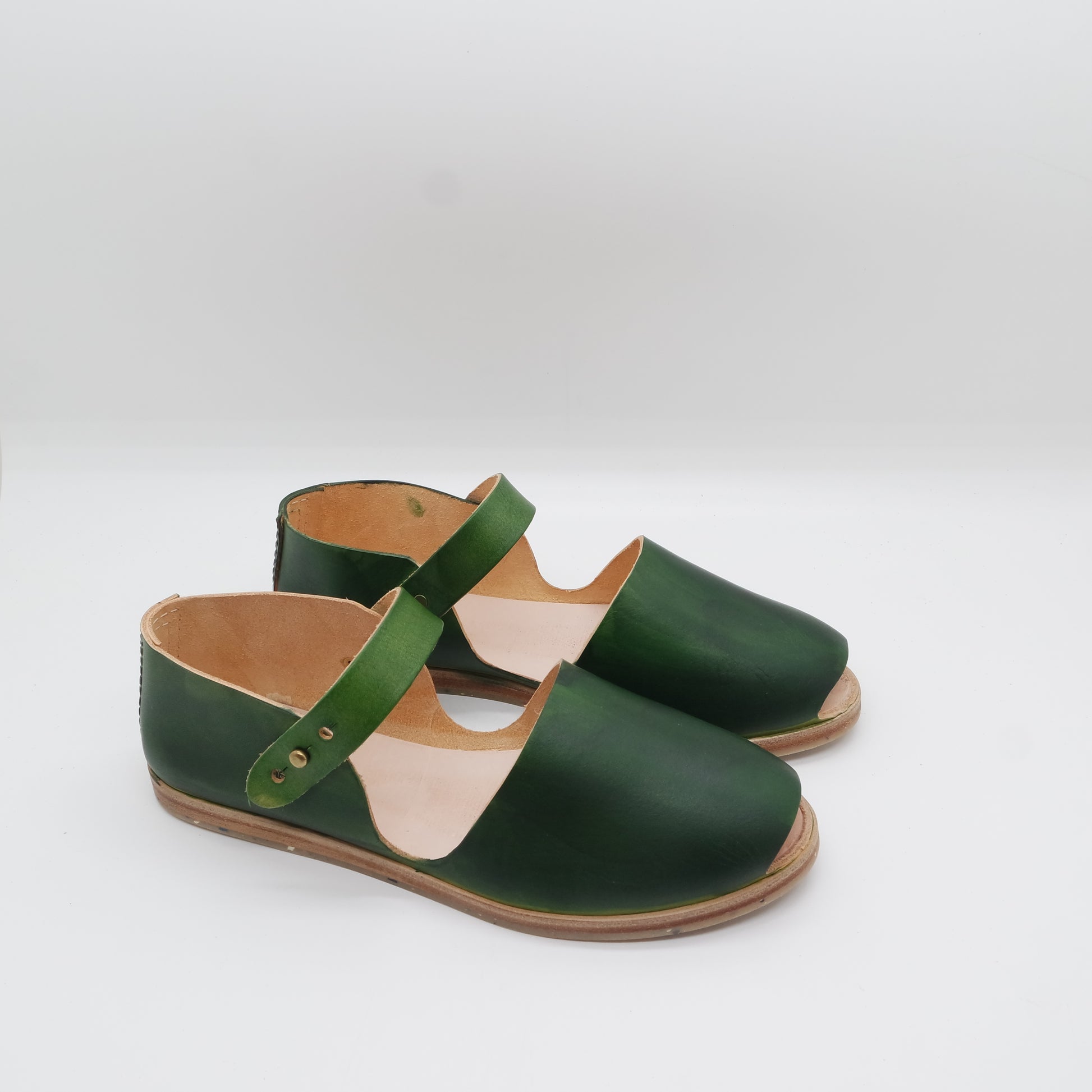 a pair of handmade green shoes on a white surface